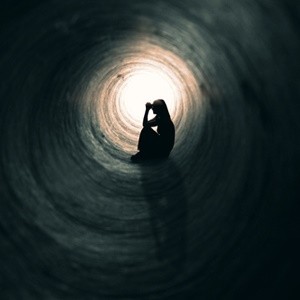 woman alone in pain sitting in tunnel praying